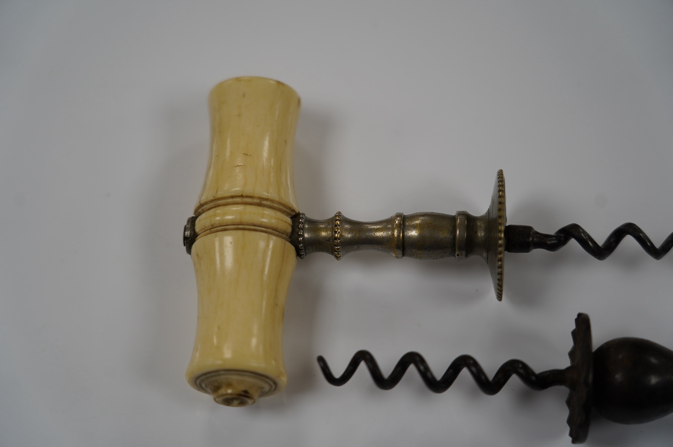 Two early 19th century bone handled corkscrews, one in steel with brush, the other in brass. Condition - good, brass example was silvered, small vacant hole to one end of the handle, no loop or ring